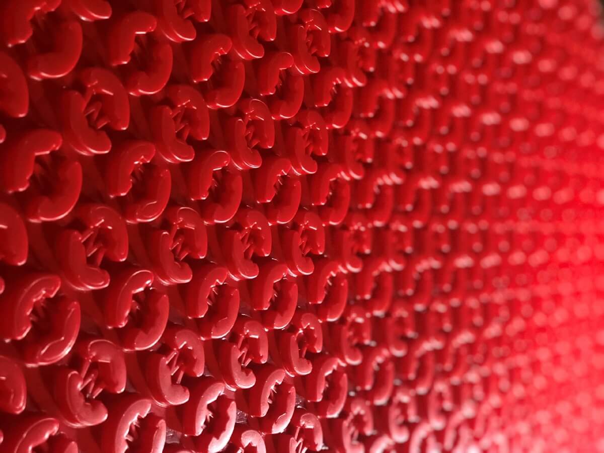 Close-up of a textured red surface of underfloor heating mat with a pattern. DCM pro v3 eco friendly heating.