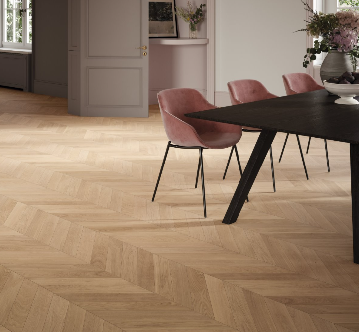 Dining area with wooden floor, pink chairs, and a black table.