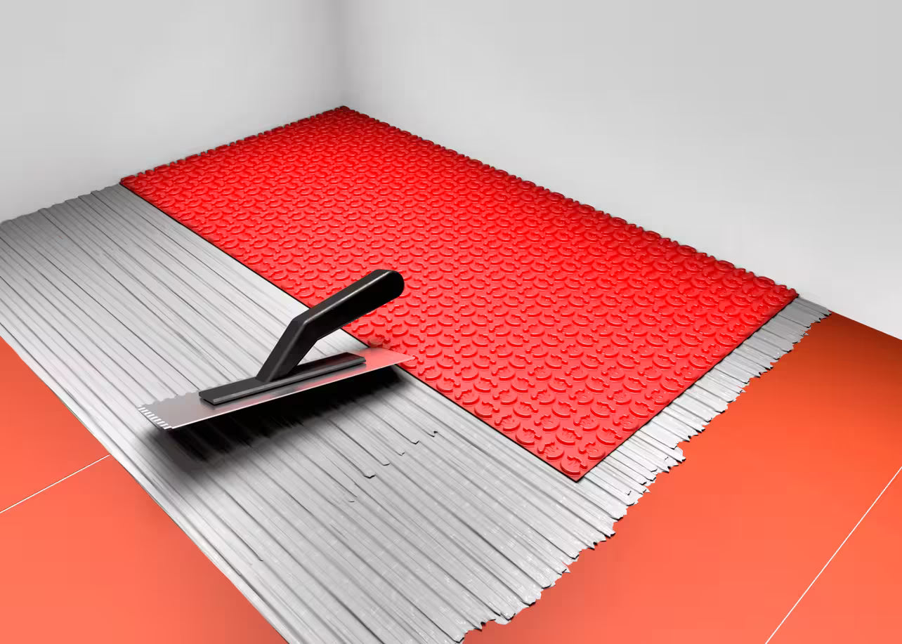 Underfloor heating DCM Fleece backing or Peel and Stick. Red tile leveling system with a trowel on a gray background