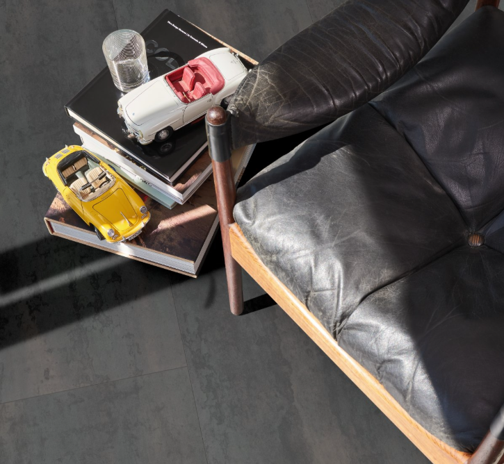 Crude Steel laminate flooring satin finish close-up in a trendy room with leather chair, books and toy cars