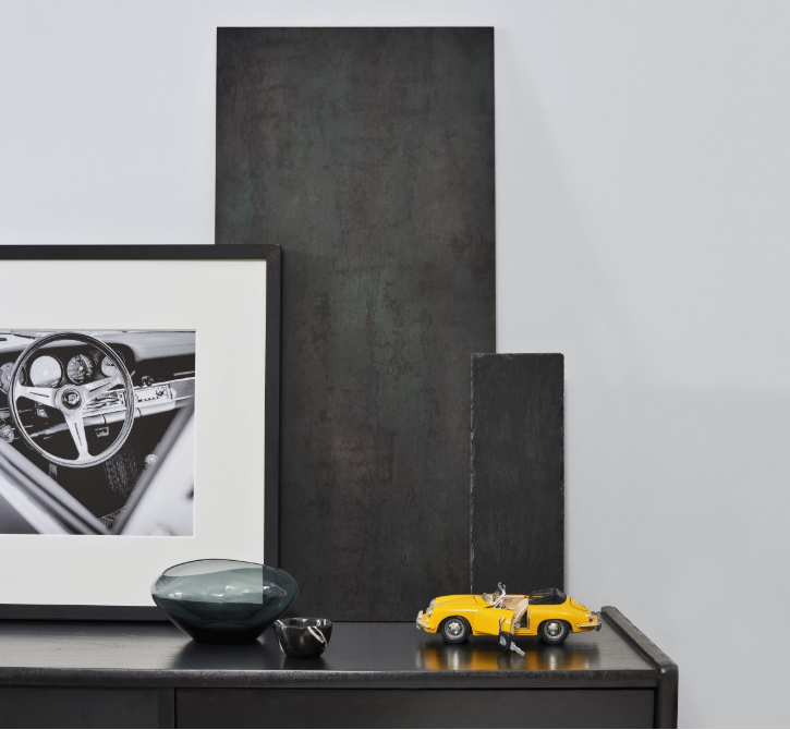 Crude Steel laminate backed against a white wall with a framed picture of a car interior on a shelf with decorative items.