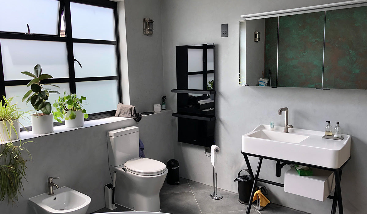 Infrared towel heater on a wall beside a bathroom sink and a large window