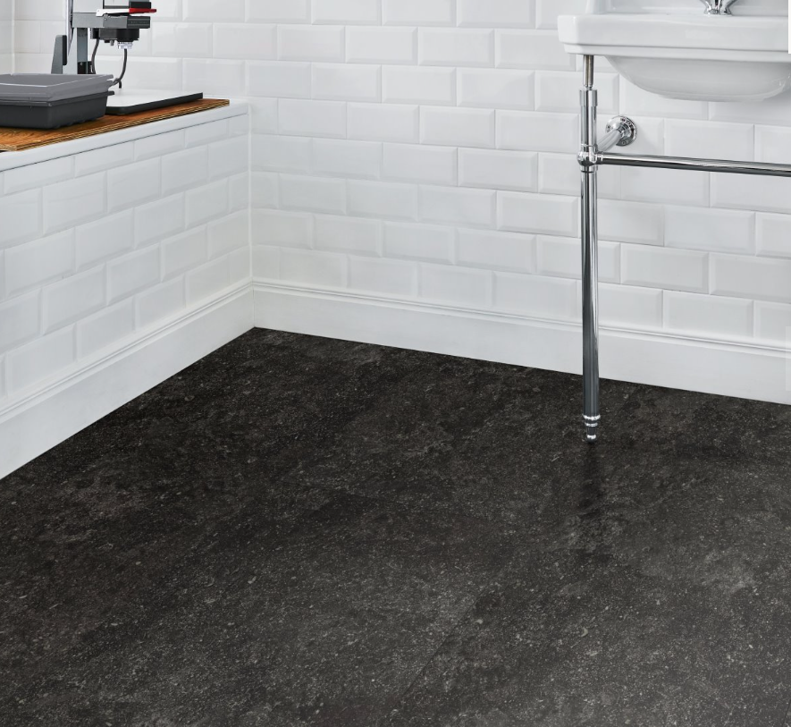 Bathroom with dark gray and black floor tiles and white tiled walls.