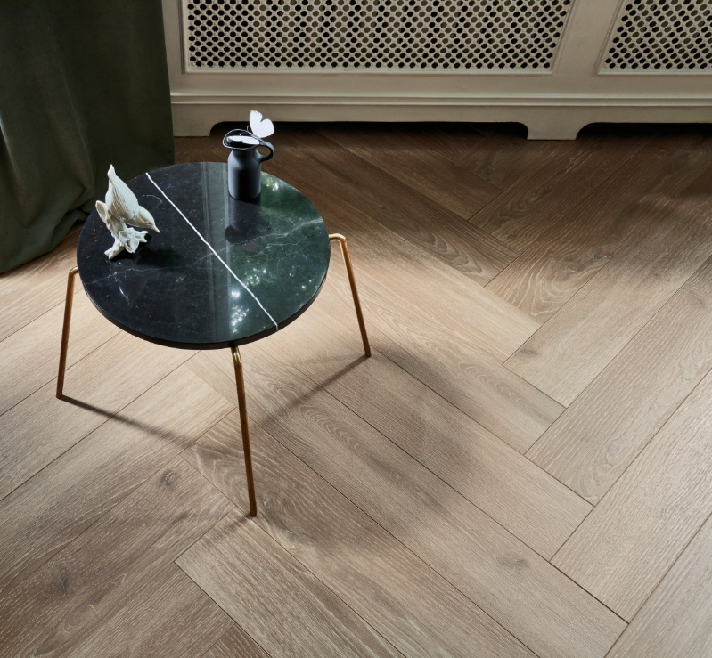 Small round table with a marble top and bronze legs on a wooden floor.