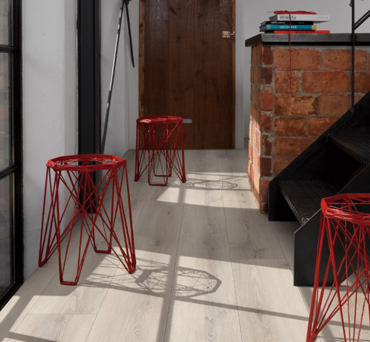 Red metal stools in a modern interior setting with Wide Plank flooring, a wooden door and brick wall.