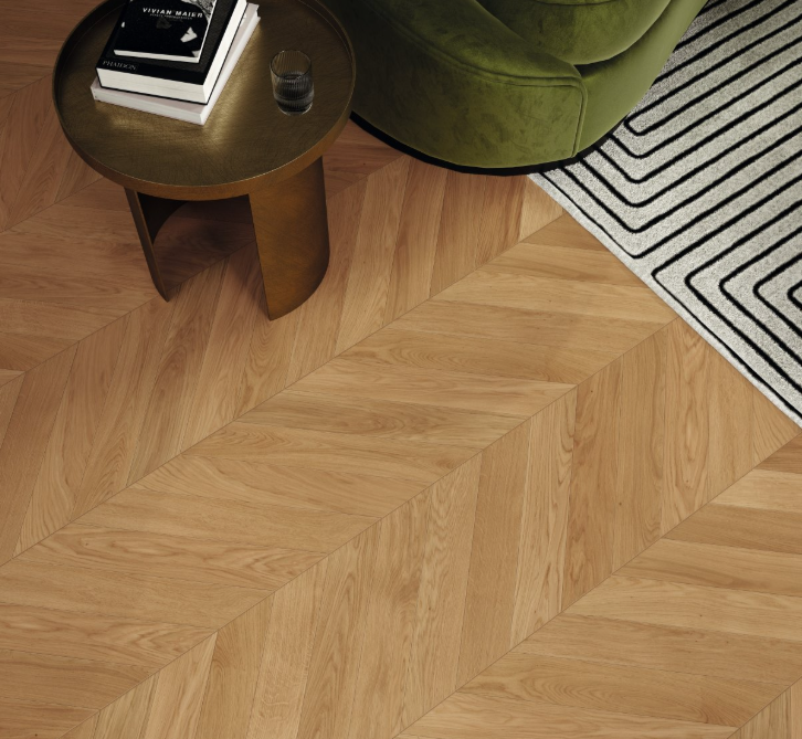 Wooden floor with a chevron pattern, green chair, and small table with books.