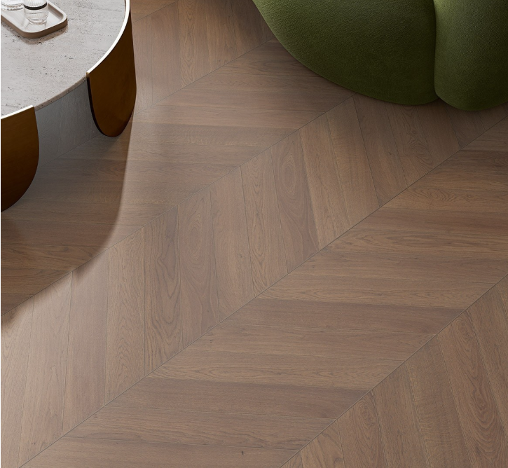 Wooden floor with herringbone pattern and a green cushioned chair in the corner.