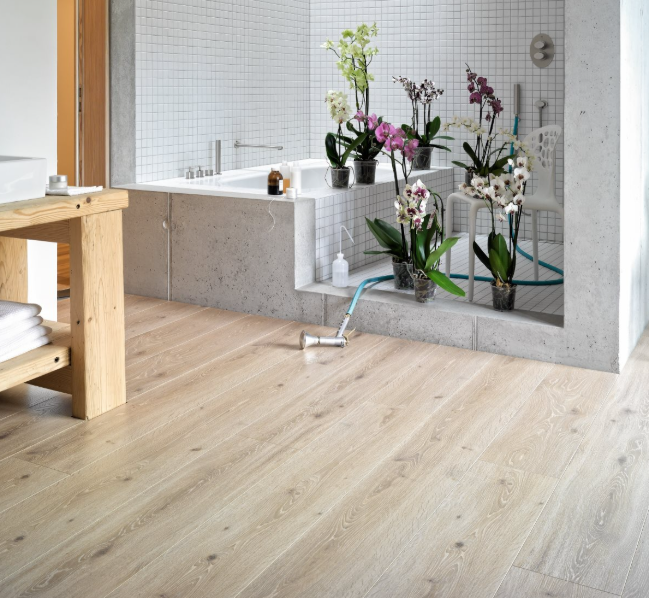 Oak Castell Limed laminate flooring installed in a spacious modern bathroom with lots of flowers.