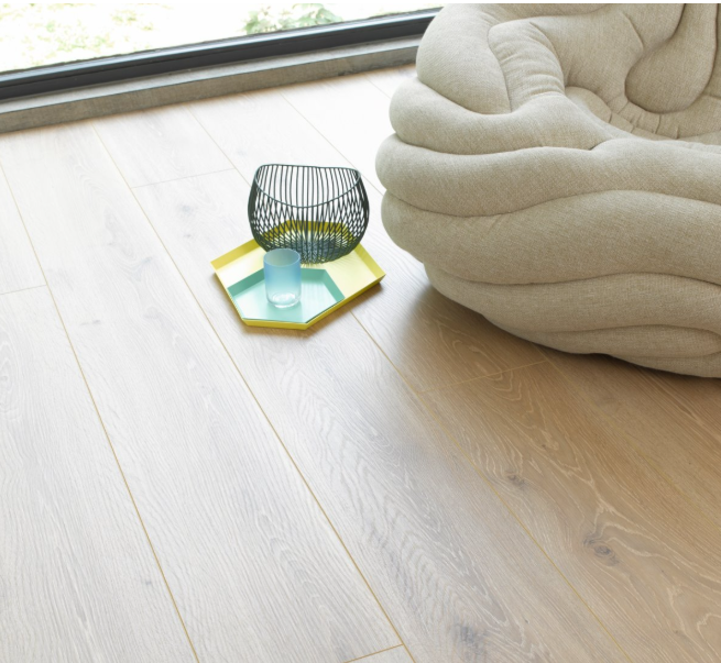 Beige cushion on installed Oak Castell Limed laminate flooring with a small table and decorative item.