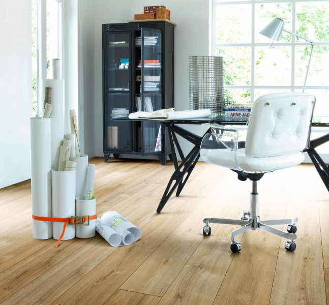 Extra-long Parador Oak Nova Limed laminate flooring in a bright open-plan office interior with desk, chair and work plans or documents.