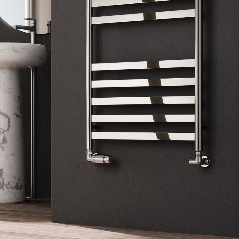 Chrome towel radiator mounted on a dark wall in a bathroom setting.