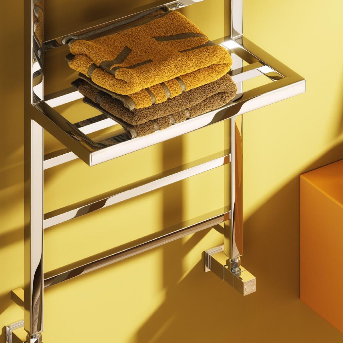 Chrome towel rack with folded towels against a yellow wall