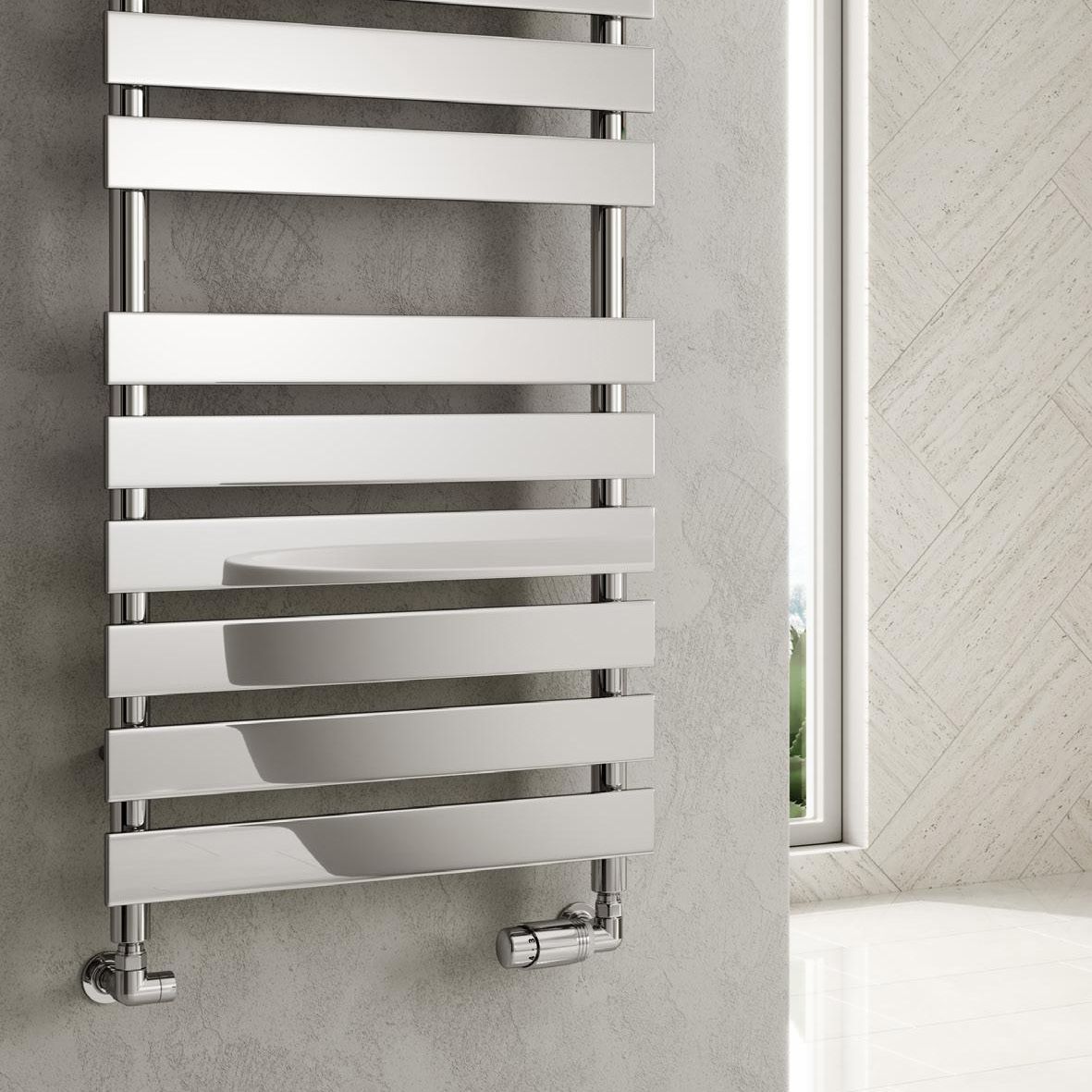 Chrome towel radiator mounted on a gray wall with a window in the background